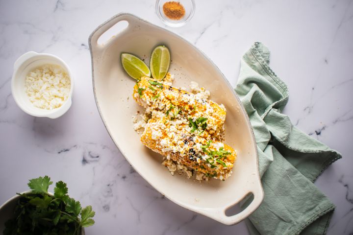 Mexican street corn on the cob with mayo, queso fresco, lime, cilantro, and chili powder.