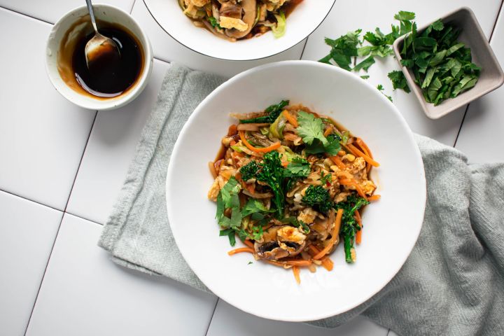 Moo shu vegetables with eggs and hoisin sauce served in a bowl with cabbage, broccoli, and mushrooms.