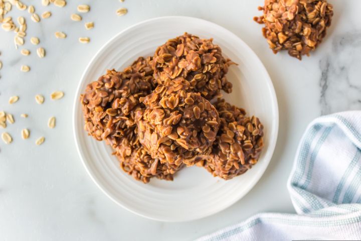 No bake peanut butter oatmeal cookies on a plate with loose oats on the side. 