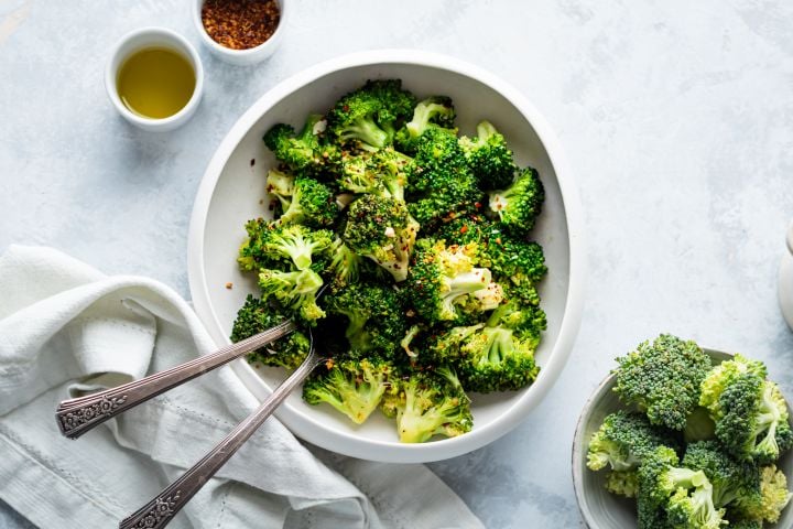 Pan fried broccoli with garlic, olive oil, and red pepper flakes in a white bowl.