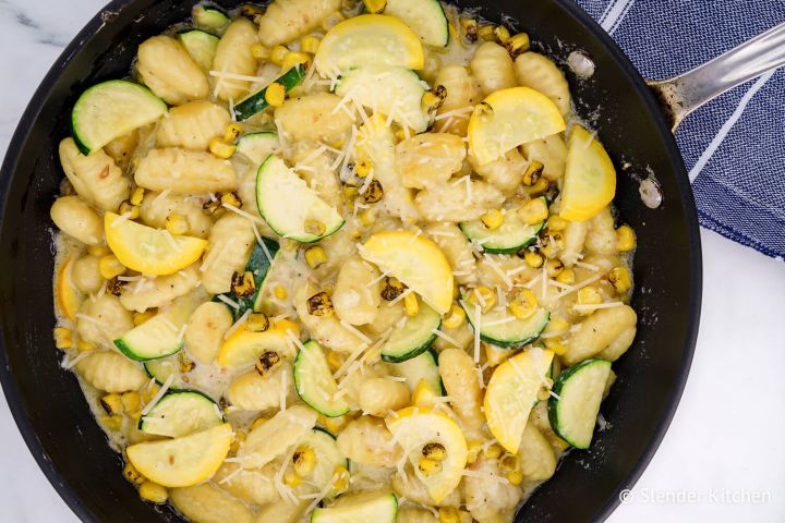Gnocchi with zucchini and corn in cream sauce in a skillet.