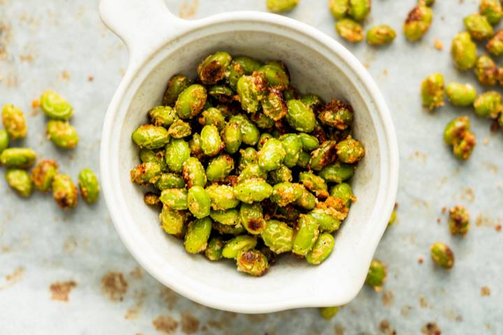 Roasted garlic edamame with crispy browned edges and Parmesan cheese in a bowl.