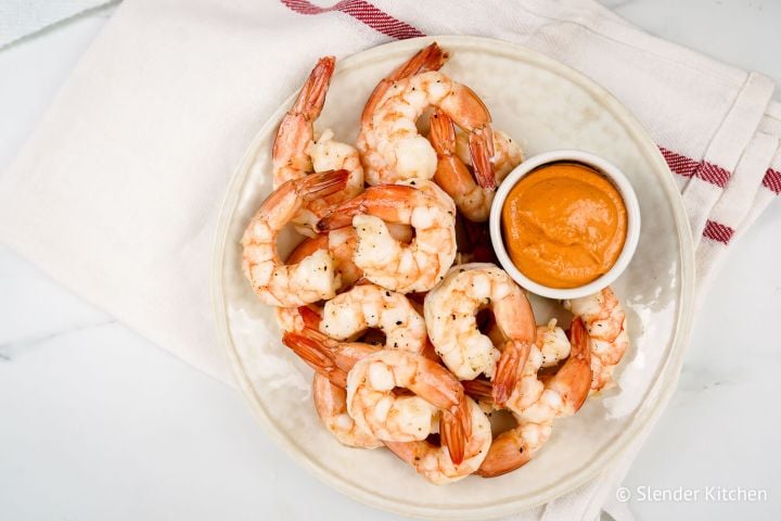 Shrimp cocktail with a small bowl of sauce on a white plate.
