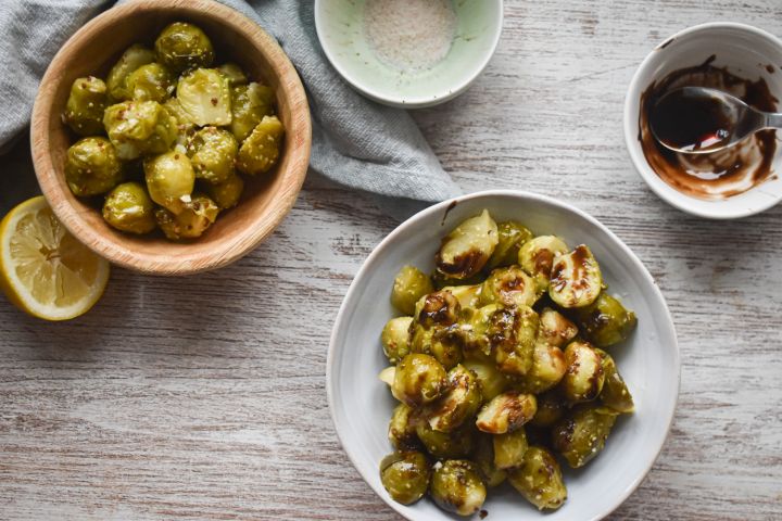 Slow cooker Brussels sprouts in a bowl with Parmesan cheese, lemon, and balsamic glaze.