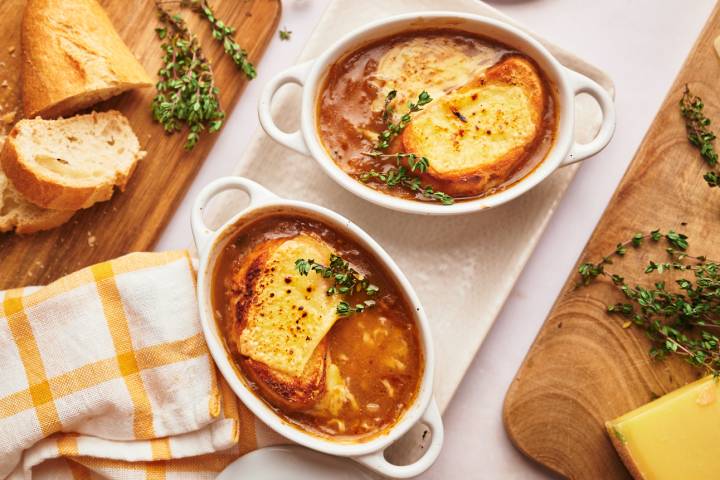 Slow Cooker French Onion soup in a bowl with bread and melted cheese.