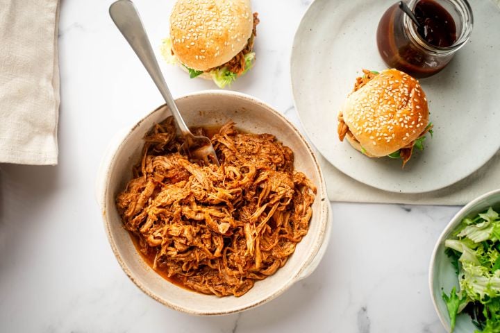 Slow cooker spicy pulled pork with shredded pork tenderloin in spicy barbecue sauce in a bowl.