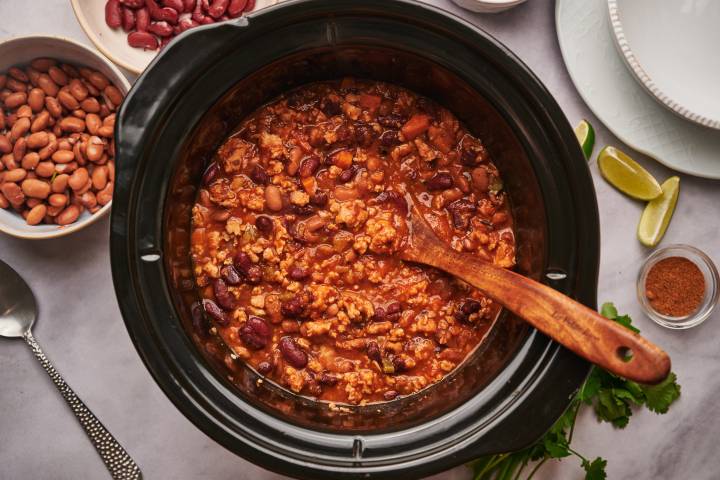 Slow cooker turkey chili with ground turkey, pinto beans, kidney beans, and tomatoes in a slow cooker.
