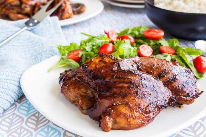 Grilled Sriracha chicken on a plate with a small salad.
