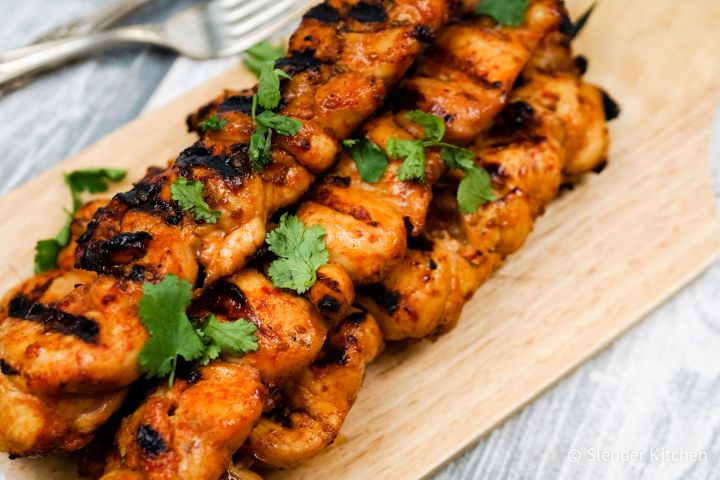 Sriracha teriyaki chicken skewers on a plate with chopped cilantro.