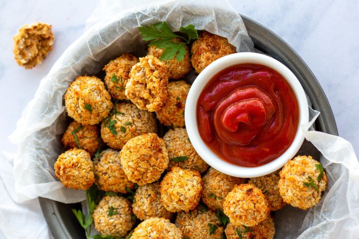 Vegetarian chickpea nuggets in a baking dish with fresh parsley and ketchup.