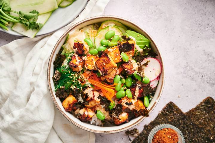 Vegetarian sushi bowl with avocado, rice, seaweed, edamame, and tofu.