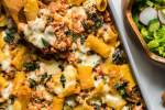Turkey and vegetable baked ziti in a casserole dish with melted cheese and fresh basil.