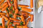 Baby carrots that have been roasted with olive oil and honey on a baking sheet.
