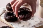 Paleo chocolate pumpkin brownies being picked up by a hand off a wooden cutting board.