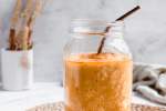 Pumpkin spice smoothie with pumpkin and oats in a glass mason jar with a straw.
