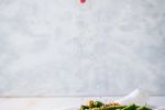 Green beans with sesame seeds being sprinkled on top.