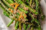 Asian green beans with sesame oil, sesame seeds, soy sauce, and garlic on a plate.