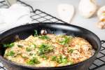 Healthy hashbrown casserole with eggs and veggies in a cast iron skillet.