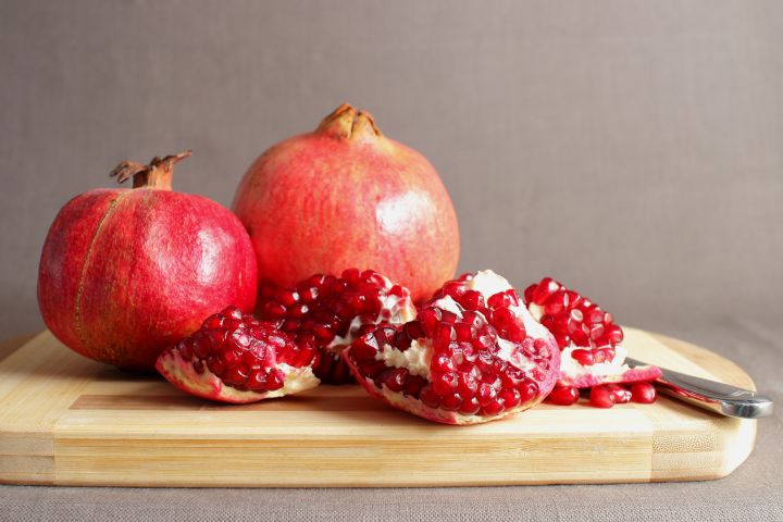 Pomegranates on a cutting board showing the arils inside.