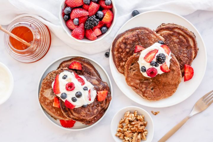 Make ahead almond flour pancakes with flaxseeds topped with berries and whipped cream.