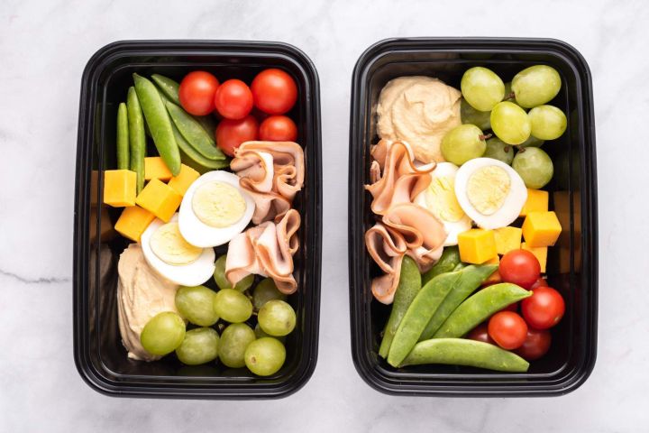 Make ahead lunch protein boxes with hard boiled eggs, deli meat, tomatoes, cheese, hummus, and grapes.