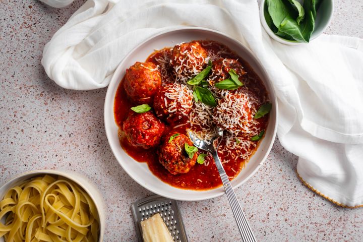 Slow cooker Italian meatballs in a bowl with marinara sauce and Parmesan cheese.