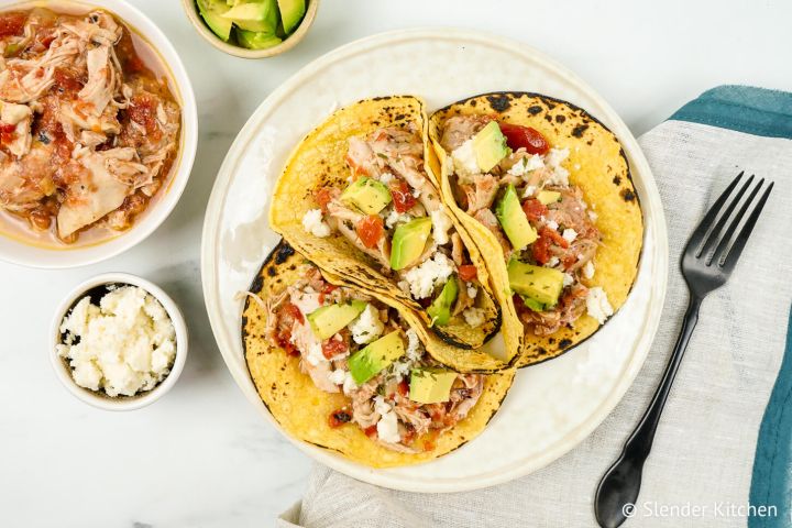 Frozen chicken cooked down to make tinga tacos with tortillas, avocado, and cheese.