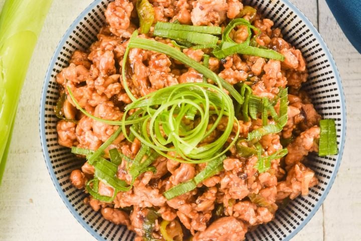 Healthy Mongolian chicken in a bowl with green onions on top.