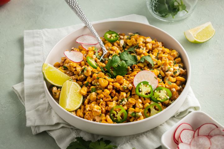 Healthy Mexican corn salad in a bowl with cilantro, corn, cheese, and jalapenos.