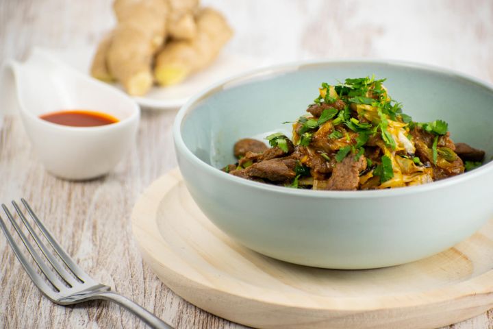 Moo Shu beef stirfry with sliced cabbage and cilantro in a blue bowl.
