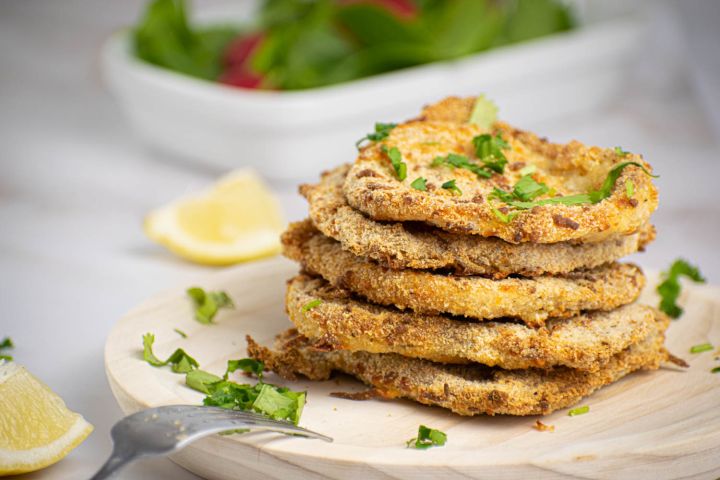 Parmesan crusted pork chops piled high with parsley and lemon slices.