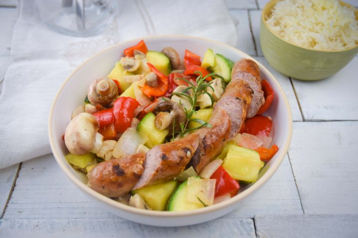 Chicken sausage and vegetable skillet with mushrooms, zucchini, peppers, onions, and rosemary in a bowl.