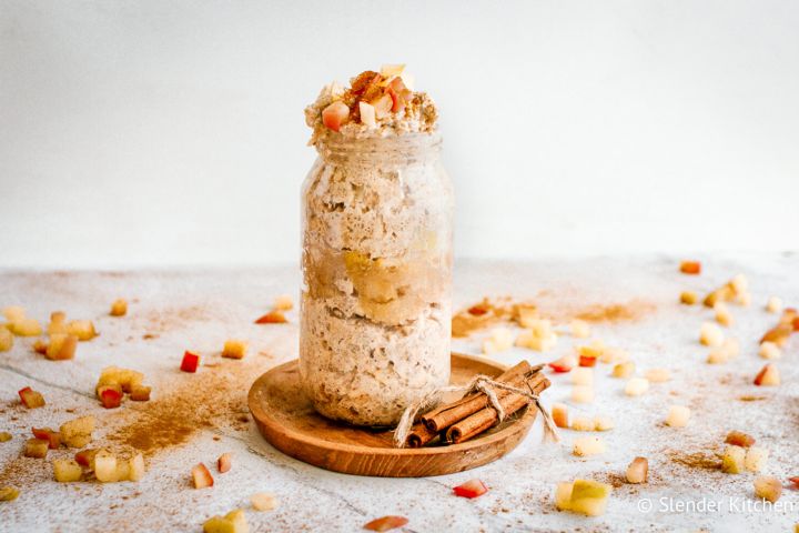 Apple cinnamon overnight oats in a glass jar with cooked apples and cinnamon on top.