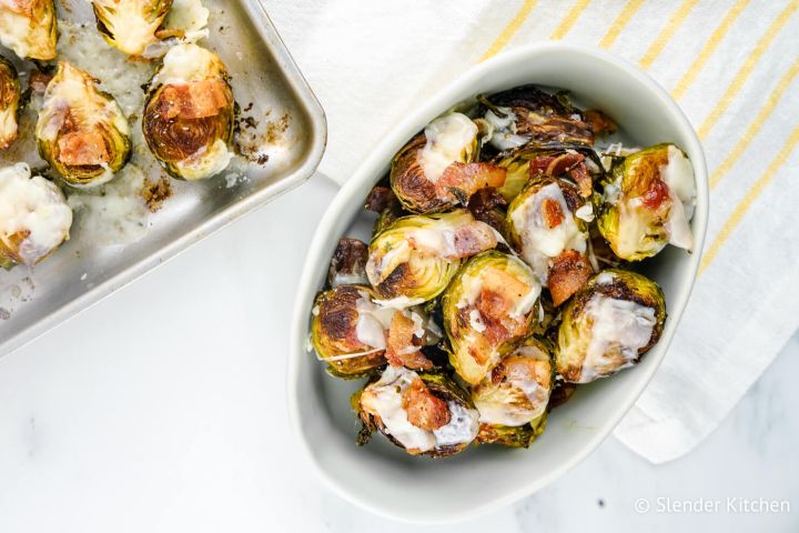 Bacon Brussel Sprouts with Parmesan cheese in a dish with a baking sheet.