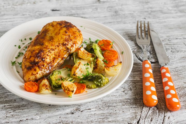 Cajun chicken with garlic on a plate with carrots and vegetables.