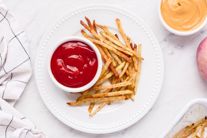 Baked skinny fries with crispy baked potatoes and turnips on a plate with ketchup.