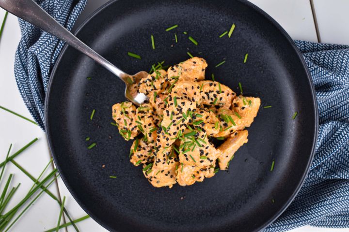 Bang Bang Chicken covered in a creamy sweet and spicy sauce with green onions and sesame seeds.