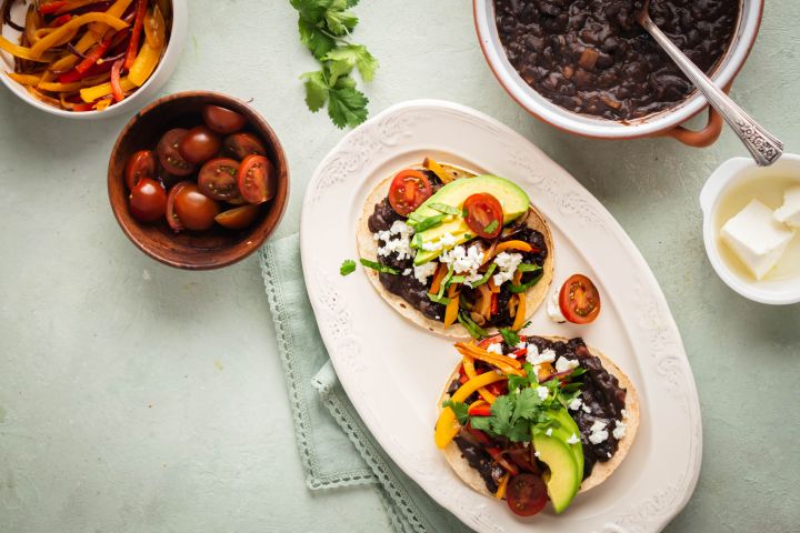 Black bean tostadas served on crispy baked tostada shells with peppers, onions, avocado, cheese, and tomatoes.