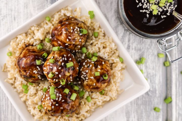 Chicken Teriyaki Meatballs on a bed of brown rice with green onions.