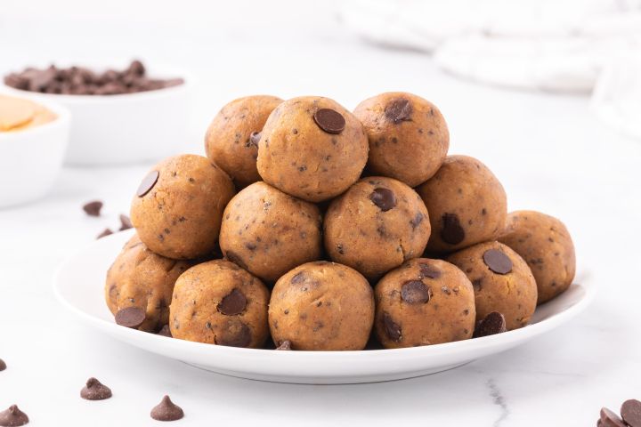 Chickpea cookie dough bites with canned chickpeas, peanut butter, maple syrup, chia seeds, and chocolate chips stacked on a plate.