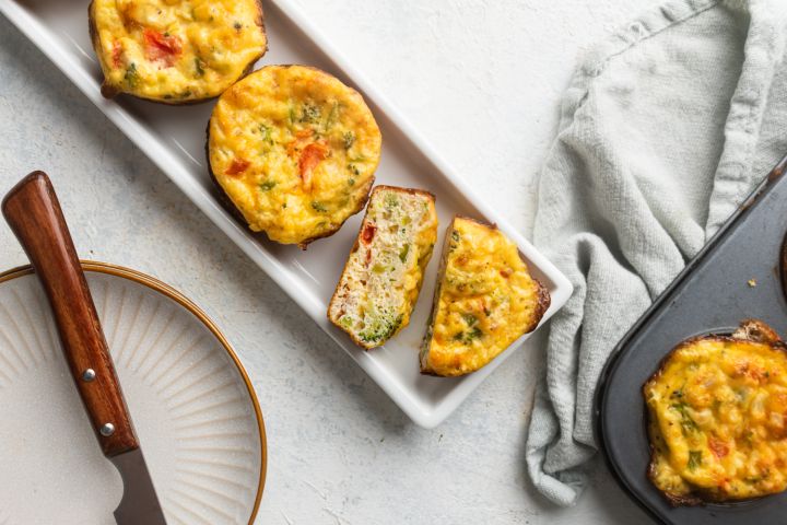 Cottage cheese muffins with mushrooms, tomatoes, and spinach on a wooden board.