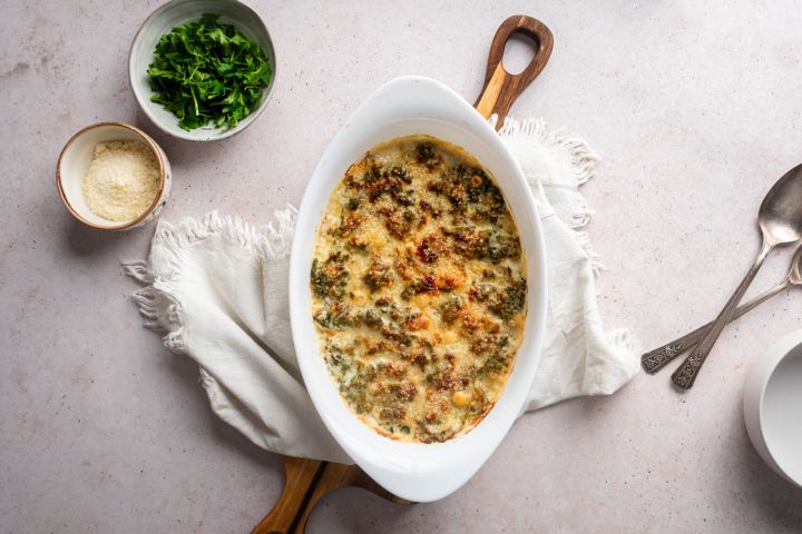 Creamed kale with tender kale cooked with cream cheese, milk, and Parmesan cheese in a white baking dish,