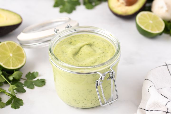Creamy avocado dressing made with avocado, Greek yogurt, cilantro, lime juice, and garlic in a small glass jar.