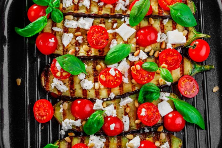 Grilled eggplant with cherry tomatoes, feta cheese, basil, and pine nuts.