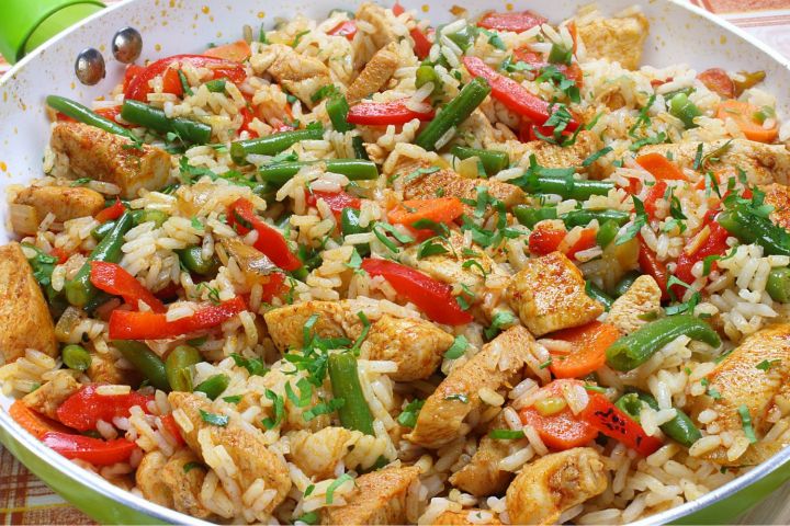Healthy chicken fried rice with veggies on a large plate. 
