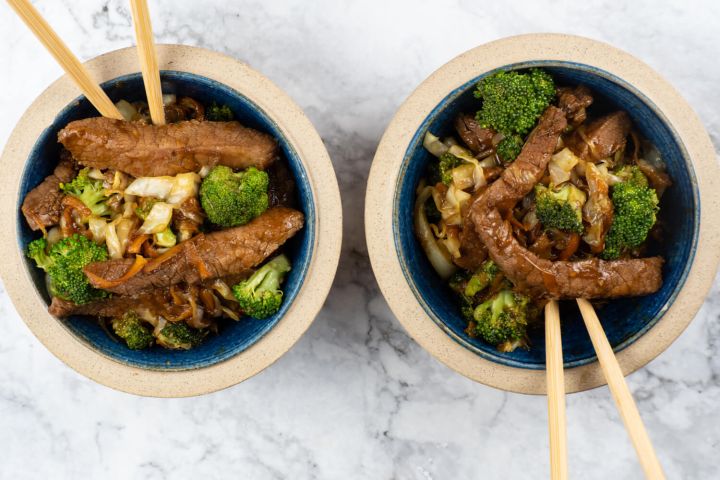 Hoisin pork stir fry with cabbage, broccoli, and carrots in a wooden bowl.