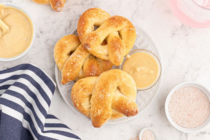 Homemade soft pretzels made with two ingredient dough and sprinkled with salt on a white plate.