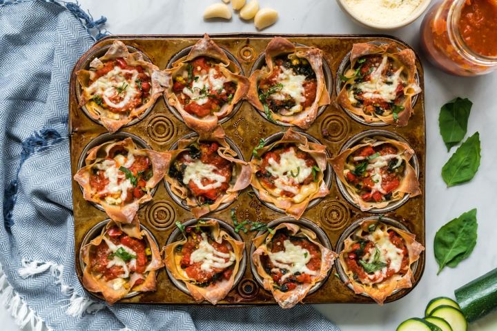 Lasagna cupcakes with ricotta cheese, vegetables, and mozzarella cheese baked in a muffin tin with marinara sauce.
