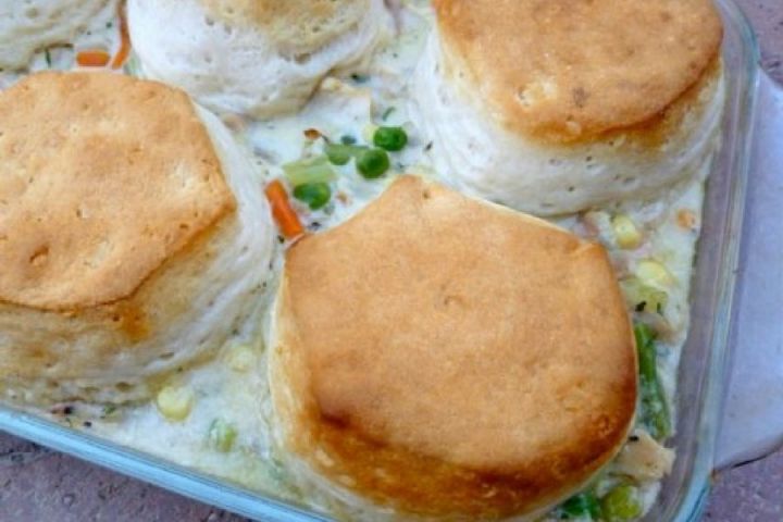 Lightened up chicken and biscuit pie in a baking dish with chicken, carrots, celery, and corn.