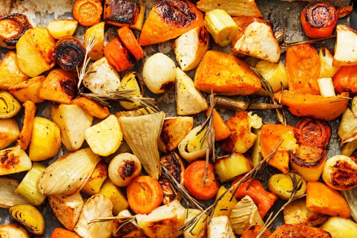 Low carb roasted root vegetables including carrots, onions, leeks, turnips, rutabaga, and rosemary on a sheet pan.